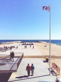 People on pier at mediterranean sea against sky