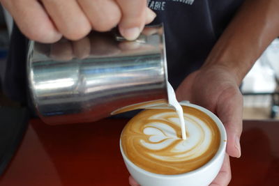 Close-up of hand holding coffee on table