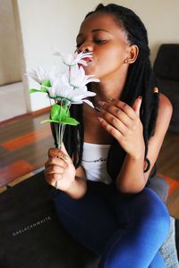 Young woman looking down while sitting on sofa at home