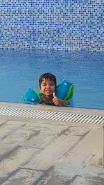 Portrait of smiling boy showing thumb up in swimming pool