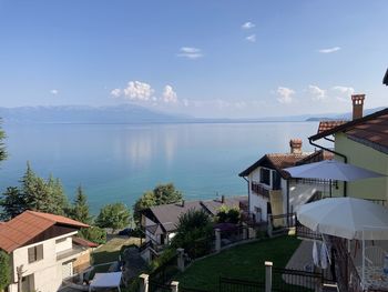 Houses by swimming pool by sea against sky