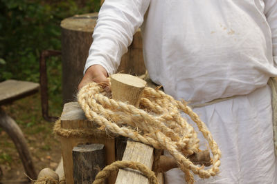 Midsection of man holding rope by railing
