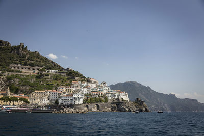 Buildings by sea against sky