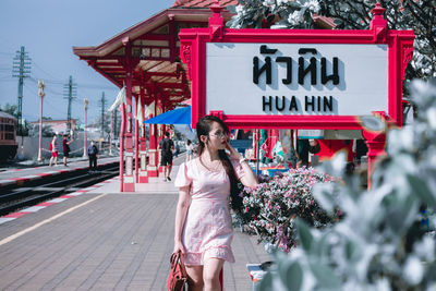 Smiling woman looking away while standing on railroad station platform