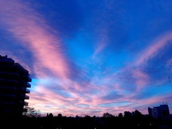 Low angle view of silhouette buildings against sky