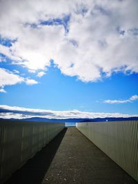 Empty footpath amidst railing against sky