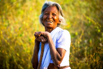 Portrait of smiling senior woman standing on field
