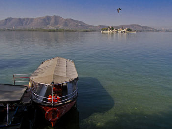 Boat moored on lake against sky