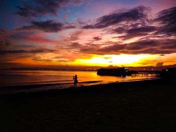 Silhouette woman standing on beach during sunset