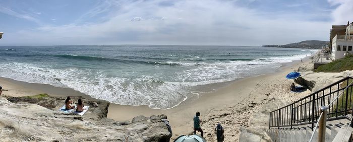 Panoramic view of people on beach against sky