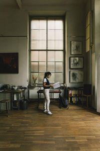 Side view of businesswoman examining document while standing at workshop