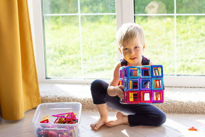 The child is playing with a multi-colored magnetic constructor, building a tower. educational toys 