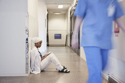 Female doctor sitting on hospital corridor floor