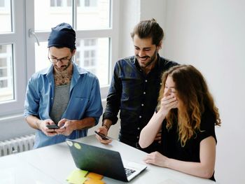 Three people looking at laptop in office meeting