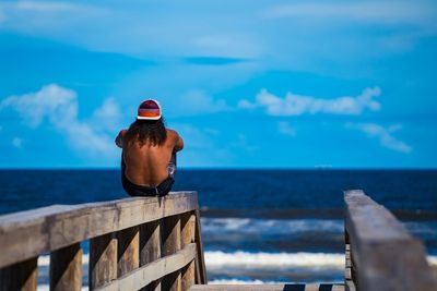 Rear view of woman standing by sea against sky