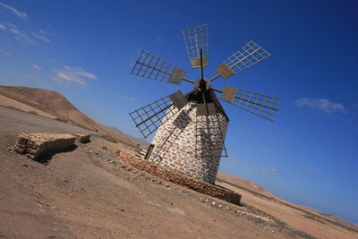 Traditional windmill on land against sky