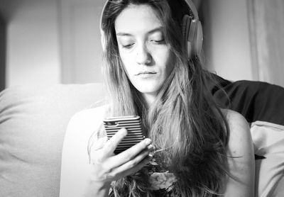 Woman listening music while using mobile phone at home