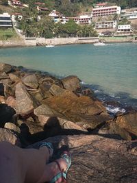 Low section of person on rock by sea