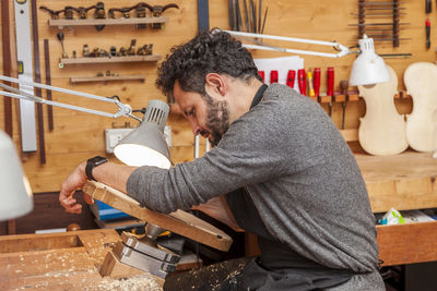 Side view of carpenter working in factory