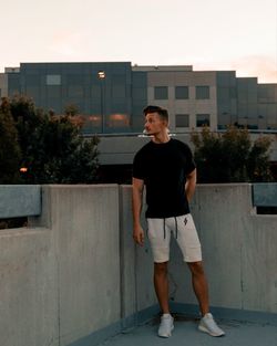 Full length of young man standing against building in city