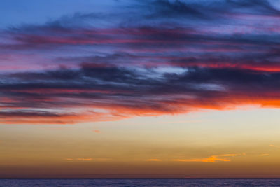 Scenic view of sea against dramatic sky during sunset