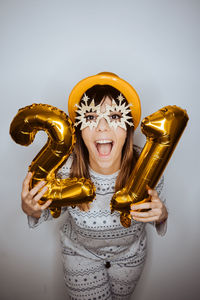 Portrait of cheerful young woman holding balloons against white background