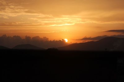 Scenic view of silhouette mountains against orange sky