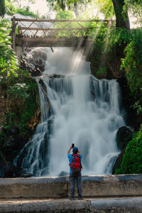 Rear view of man standing against waterfall