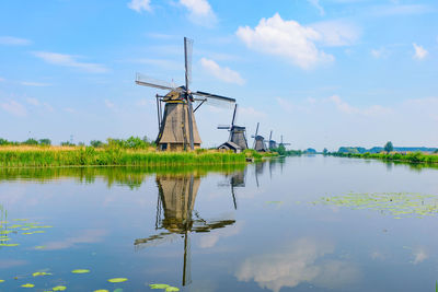 Traditional windmill on water against sky
