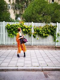 Woman with umbrella on footpath amidst plants