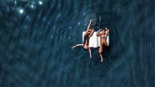 Drone view of friends floating on sea