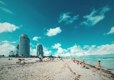 People on beach against blue sky