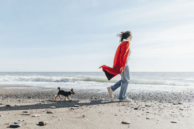 Young woman with dog looking at sea on sunny day