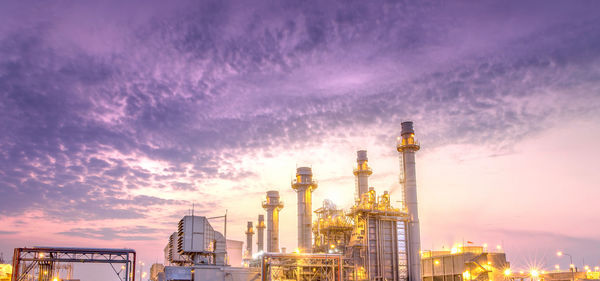 Illuminated factory against sky during sunset