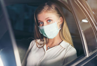 New normal. teenager sitting in the back of a car with a mask. young woman in a taxi protected