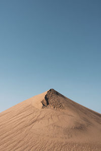 Sand dunes in desert against clear blue sky