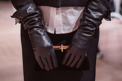 Fashion details of a classy black skirt, leather gloves and classic velvet clutch. fashion model