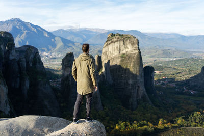 Rear view of man standing on rocks against mountains