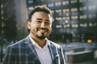 Portrait of smiling businessman standing outside office building