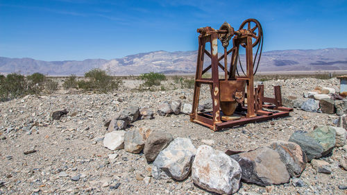 Rusty metallic structure on rocks against sky