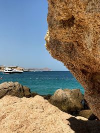 Rock formation by sea against clear sky