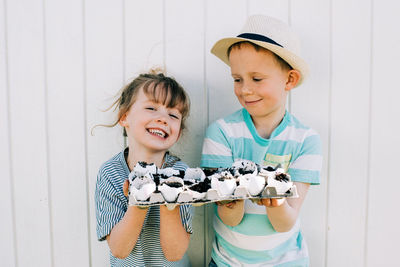 Siblings holding their planted seeds in egg shells up showing them off