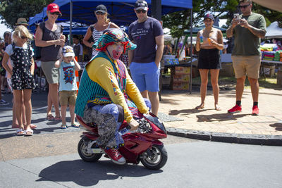 Portrait of clown riding small motorcycle at amusement park