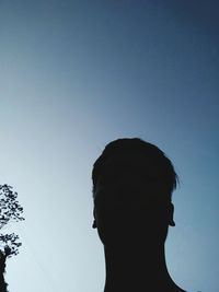 Low angle portrait of silhouette man against clear blue sky