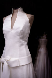 Close-up of mannequin wearing white dress against black background