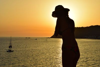 Silhouette man standing on beach against sky during sunset
