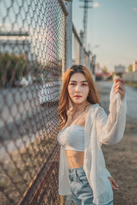 Portrait of woman standing by fence