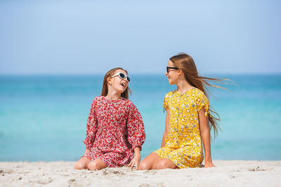 Young woman with sunglasses on beach against sky