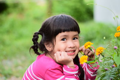Portrait of smiling girl crouching by plants at park