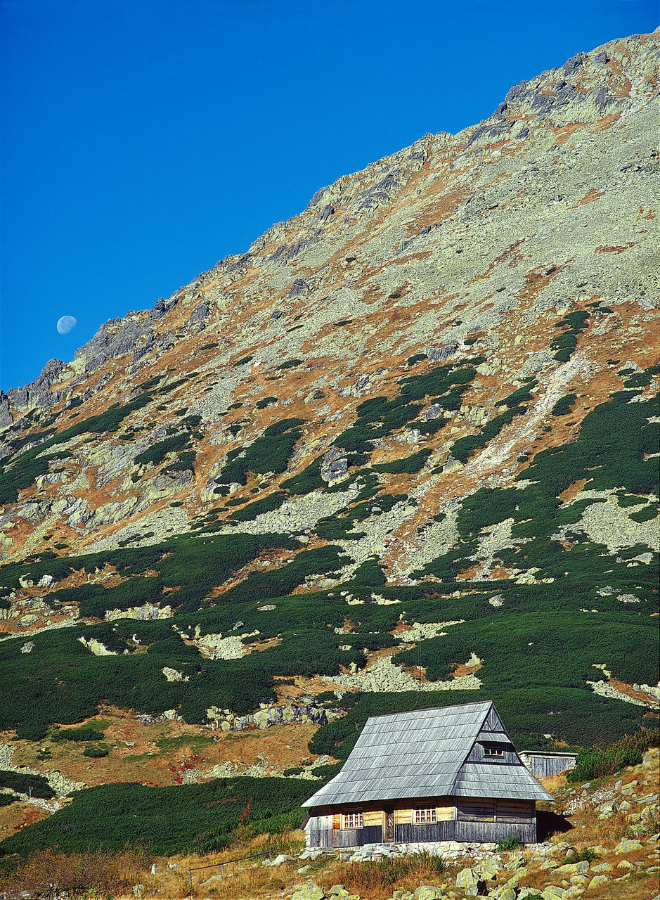 LOW ANGLE VIEW OF ROCKY MOUNTAIN AGAINST CLEAR BLUE SKY